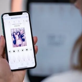 A guest holding a phone showing a booth photo with text and social sharing buttons under it