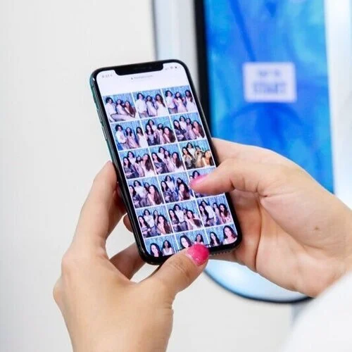 A phone held in one hand showing a grid of every photo from the night in the online gallery
