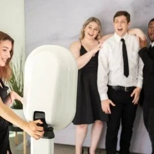 A group of wedding guests crowding into frame at the booth, laughing and shouting