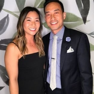A couple in formal wear photographed at the booth against a leafy backdrop