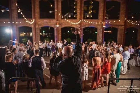 A wedding reception at night, guests gathered on the floor under string lights